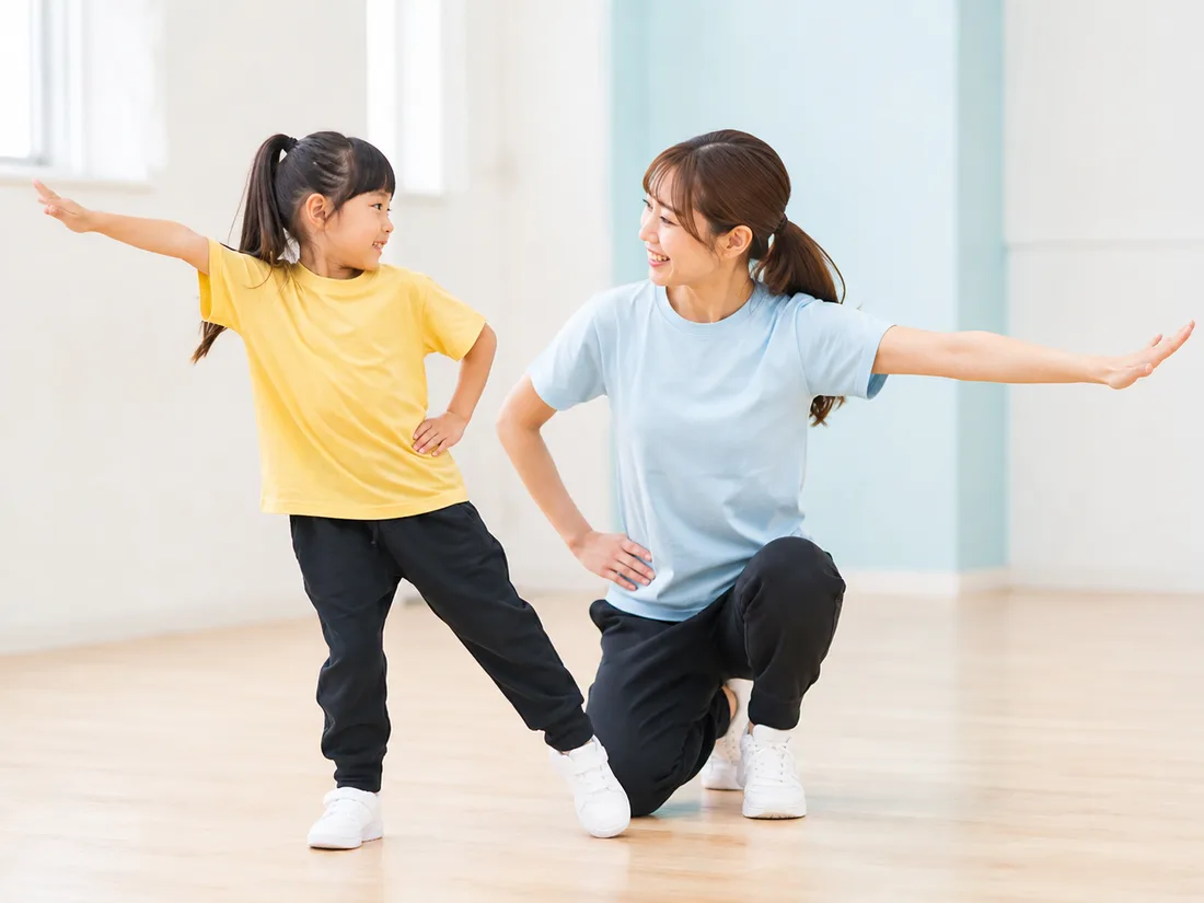 先生からやさしくダンスの動きを教わる子ども